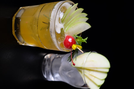 Alcoholic cocktail with apple and cherry on a black background.の写真素材