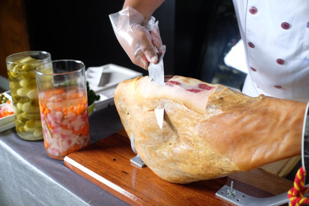 Chef cutting a piece of smoked ham on a wooden board.の写真素材