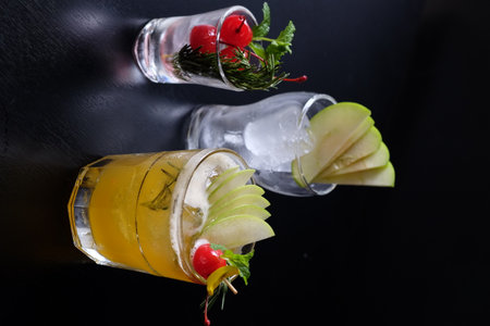 Tequila sunrise cocktail with apple, lime and rosemary on a black backgroundの写真素材