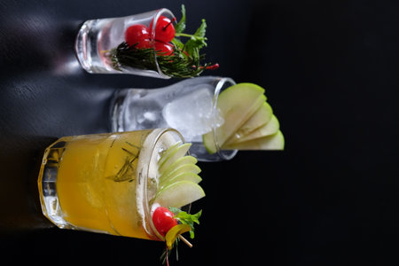 Tequila sunrise cocktail with lime, rosemary and cherry on black backgroundの写真素材