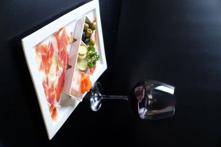 Tasty appetizer with prosciutto and olives on white plateの写真素材