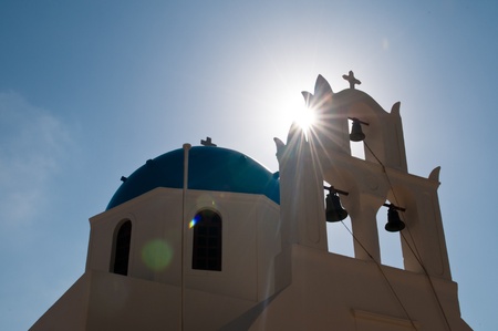 Greek church in Santorini island, Greece. Photo was taken against the sun to show the sun ray and flareの写真素材