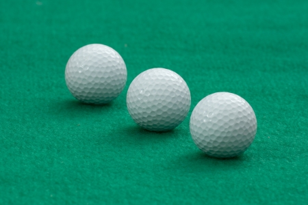 Three golf balls on green putting matの写真素材