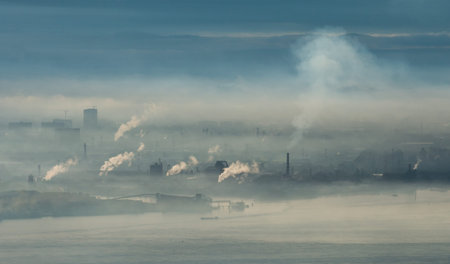 Factory area with smoke and steam coming out from chimney