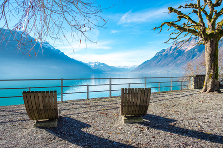 The view of mountains at Lake brienz of Switzerland with two wooden chairs as the foregroundの写真素材