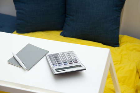working from home concept. Notebook , pen, calculator on the table on the sofa at homeの写真素材
