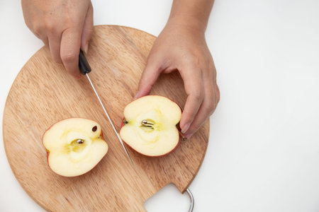 Female using knife to cut apple on the cut board