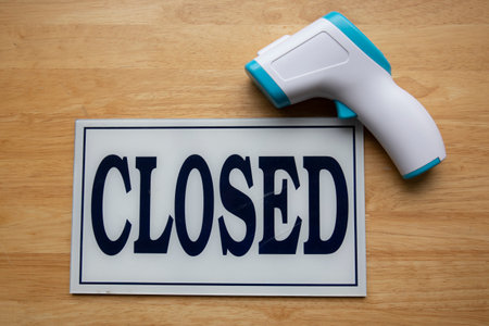 Close up shot of close sign with thermometer gun on wooden backgroundの写真素材