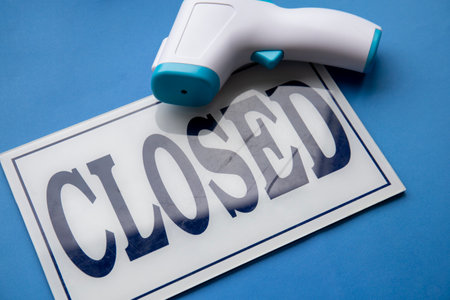 Close up shot of close sign with thermometer gun on blue backgroundの写真素材