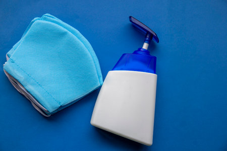 Top shot of blue sanitizer bottle and blue masks isolated on blue backgroundの写真素材