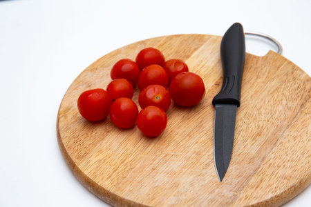 Luxury black kitchen knife and tomato on cutting board isolated on white
