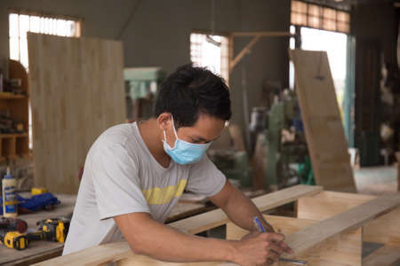 Carpenter measuring wooden board with ruler with scale in workshop. Joinery work on the production of wooden furniture. Small Business Conceptの写真素材