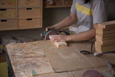 Ð¡arpenter working with wood using electric sander from workshop. Joinery work on the production and renovation of wooden furniture. Small Business Concept. Close upの写真素材