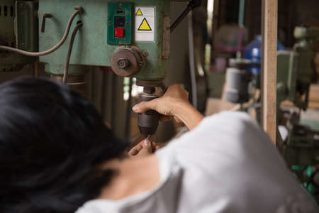 close up young male worker using a drill machine on the factoryの写真素材
