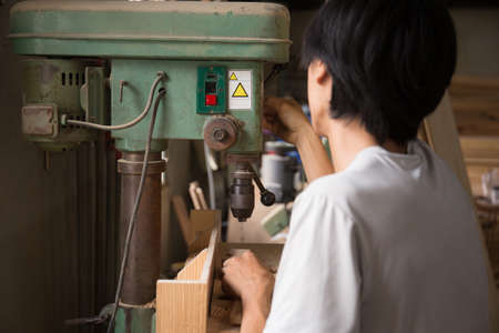 close up young male worker using a drill machine on the factoryの写真素材