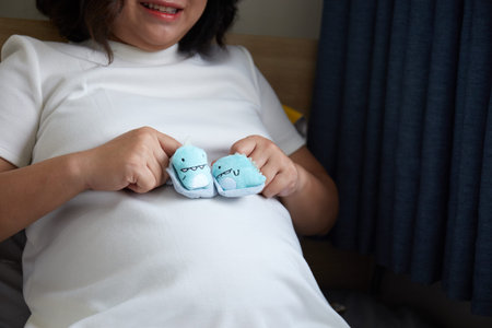 Small shoes for the unborn baby in the belly of pregnant woman