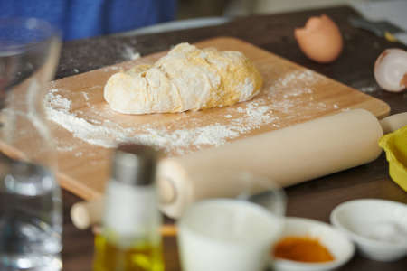 Dough on a wooden table with flour, eggs, close-up. Ingredients for bread, homemade baked goods, pizza.の写真素材