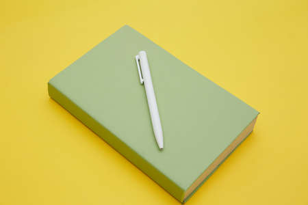 Top view of green book and pen isolated on yellowの写真素材