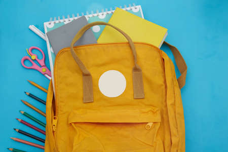 Flat lay composition with backpack and school stationery on blue backgroundの写真素材