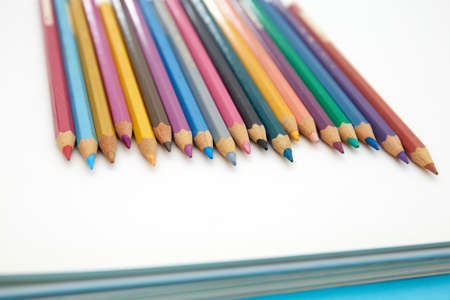 Colorful pencil crayons on a notebook on blue backgroundの写真素材