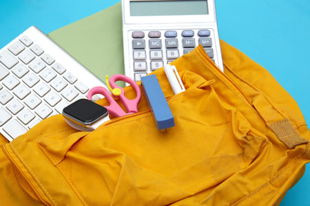 School backpack and school supplies on blue background. Back to school concept.