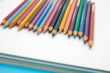 Colorful pencil crayons on a notebook on blue backgroundの写真素材