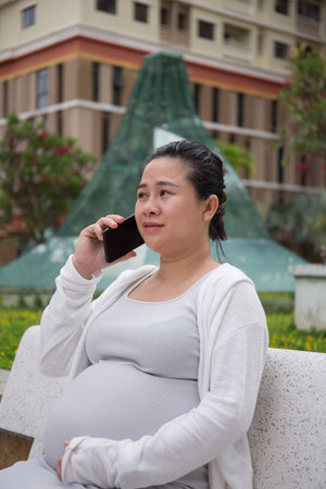 Asian Pregnant Woman in the park using smartphone