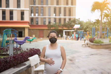 Asian Pregnant Woman Wearing Mask in the park during Covid 19の写真素材
