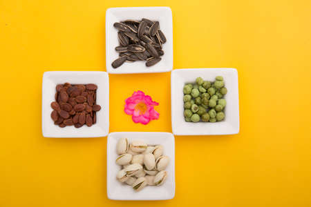 Flat lay composition with different nuts and seeds on yellow background. Top viewの写真素材