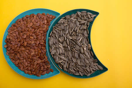 Sunflower seeds in a bowl on yellow backgroundの写真素材