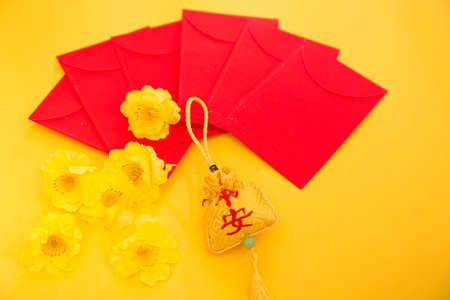 Chinese new year decorations, red envelopes and yellow flowers on yellow backgroundの写真素材