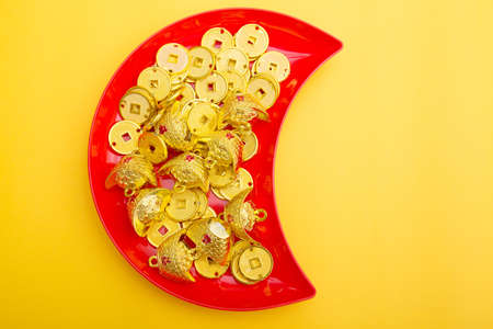 Golden coins on a red plate on a yellow background, top viewの写真素材