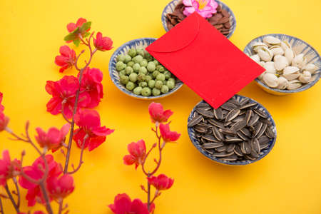 Chinese new year festival decorations on yellow background with red envelope and sunflower seedsの写真素材