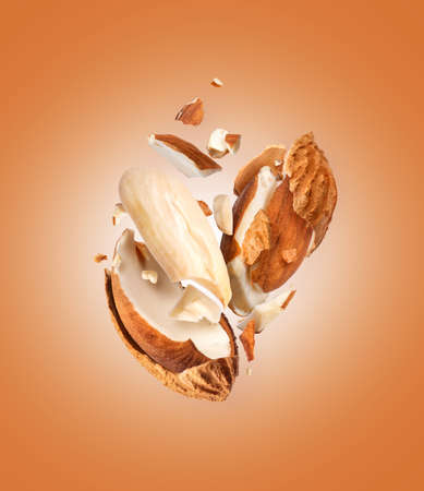 Crushed dried almonds with shell in air close up on brown backgroundの写真素材