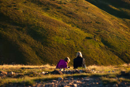 at sunset the two girls sitting in the mountainsの写真素材