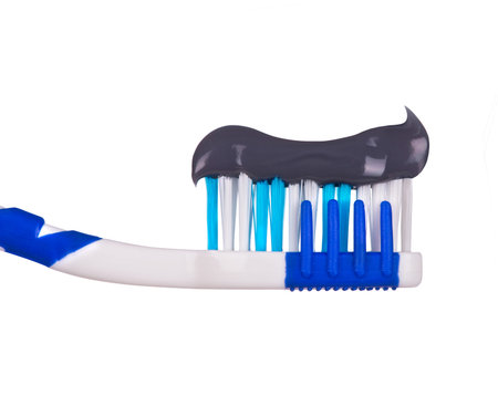 dark toothpaste on a toothbrush close-up isolated on white