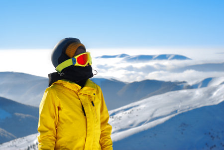 girl in a mask for snowboarding and helmet against the backdrop of snow-capped mountainsの写真素材