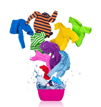 Colorful T-shirts flies out of the laundry bowl, isolated on white backgroundの写真素材