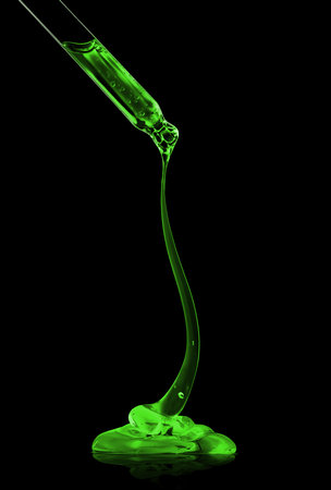Cosmetic pipette with green transparent gel close up on black backgroundの写真素材