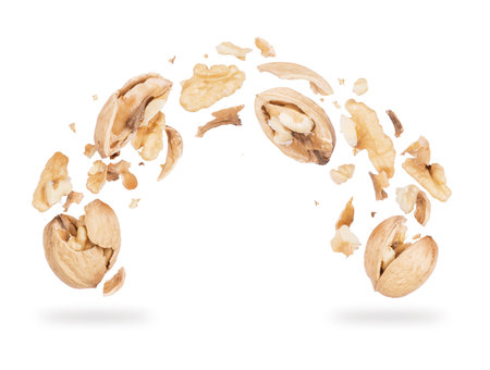 Walnuts crushed into pieces, frozen in the air on a white backgroundの写真素材