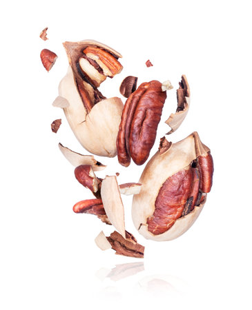 Pecan nuts crushed into pieces, frozen in the air on a white background
