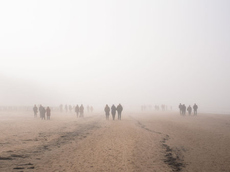 Walking people in dense fog in the sand