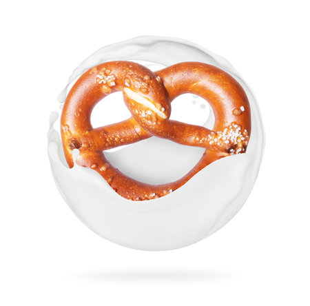 Freshly baked pretzel in milk splashes, isolated on a white backgroundの写真素材