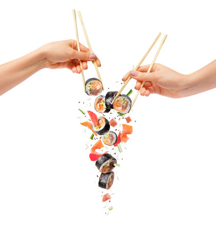 Falling sushi rolls with wooden chopsticks in female hands, isolated on white backgroundの写真素材