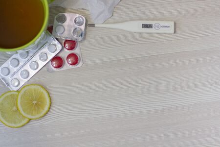 Cold and flu concepts. A cup of hot tea with a lemon. Treatment of colds and flu. A flu medicaments, thermometer, pills and paper wipesの写真素材