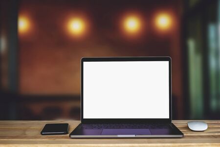 Laptop computer with blank white screen on the table, background wall blurの写真素材