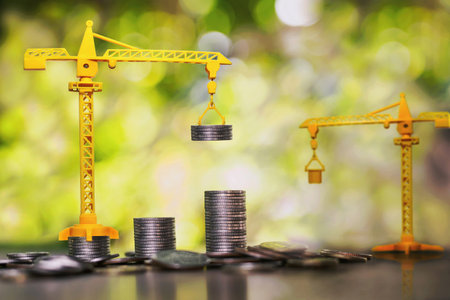 Construction cranes are stacking coins. business investment ideasの写真素材
