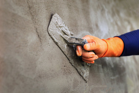 Plastering concrete to create industrial worker wall background with plastering toolsの写真素材