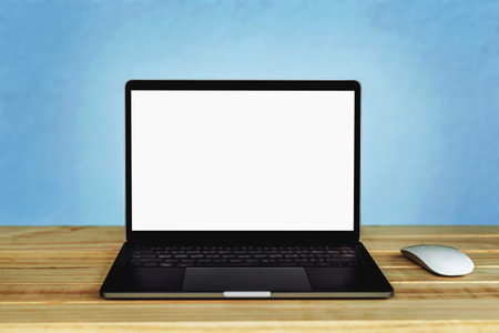 Laptop computer with blank white screen on the table, background wall blur