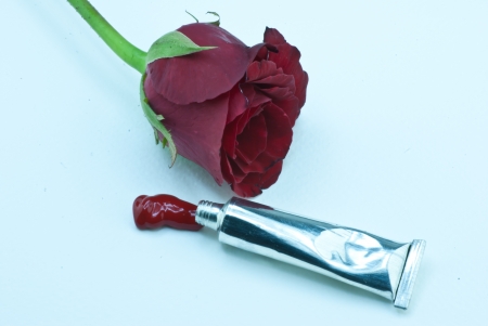 Red color tube and rose on white paperの写真素材